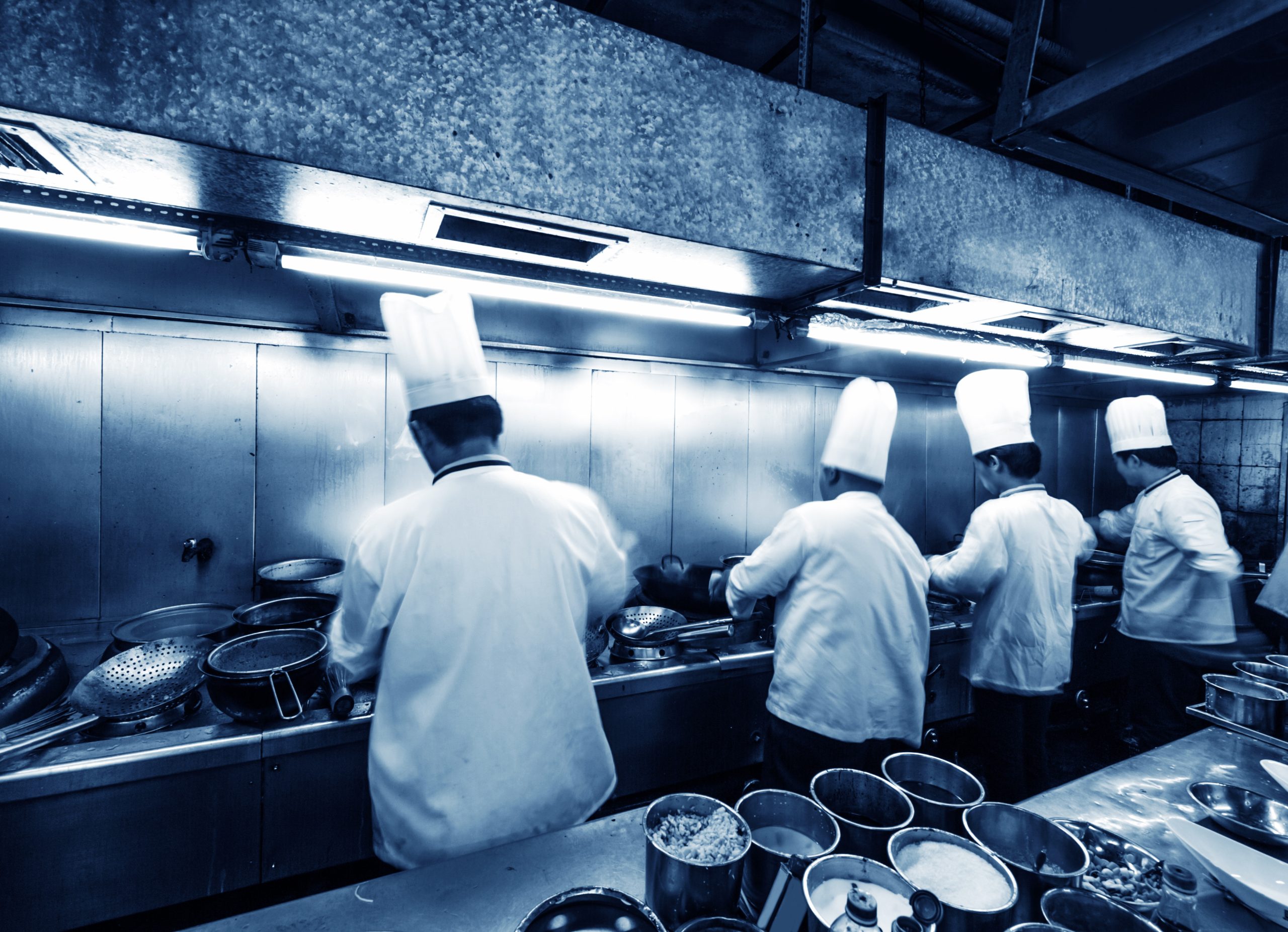 Crowded kitchen, a narrow aisle, working chef.